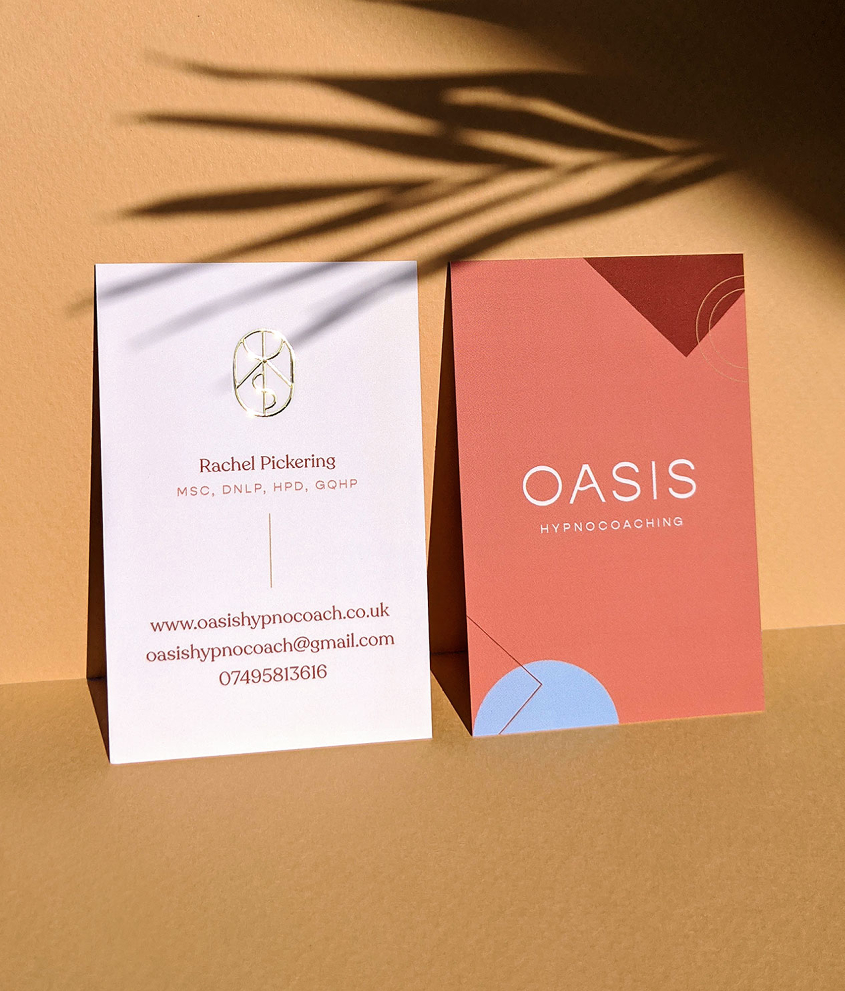 An Oasis business card in terracotta, the wordmark reversed out in cream