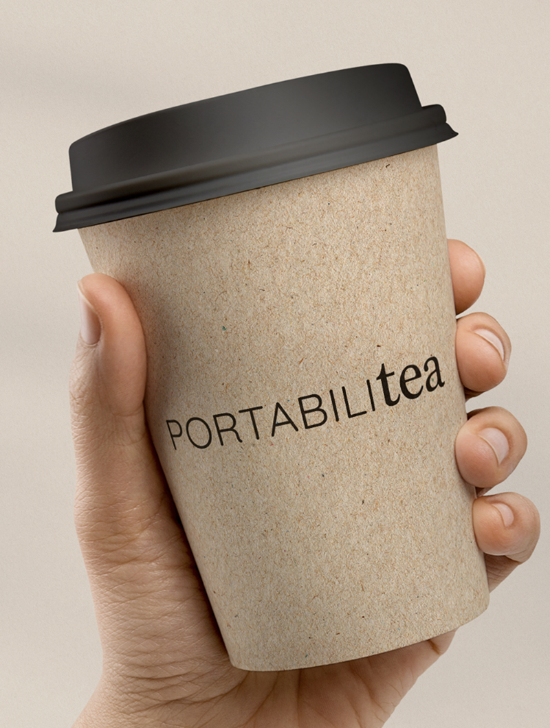 A hand holding a kraft takeaway cup with a black lid, printed PORTABILItea