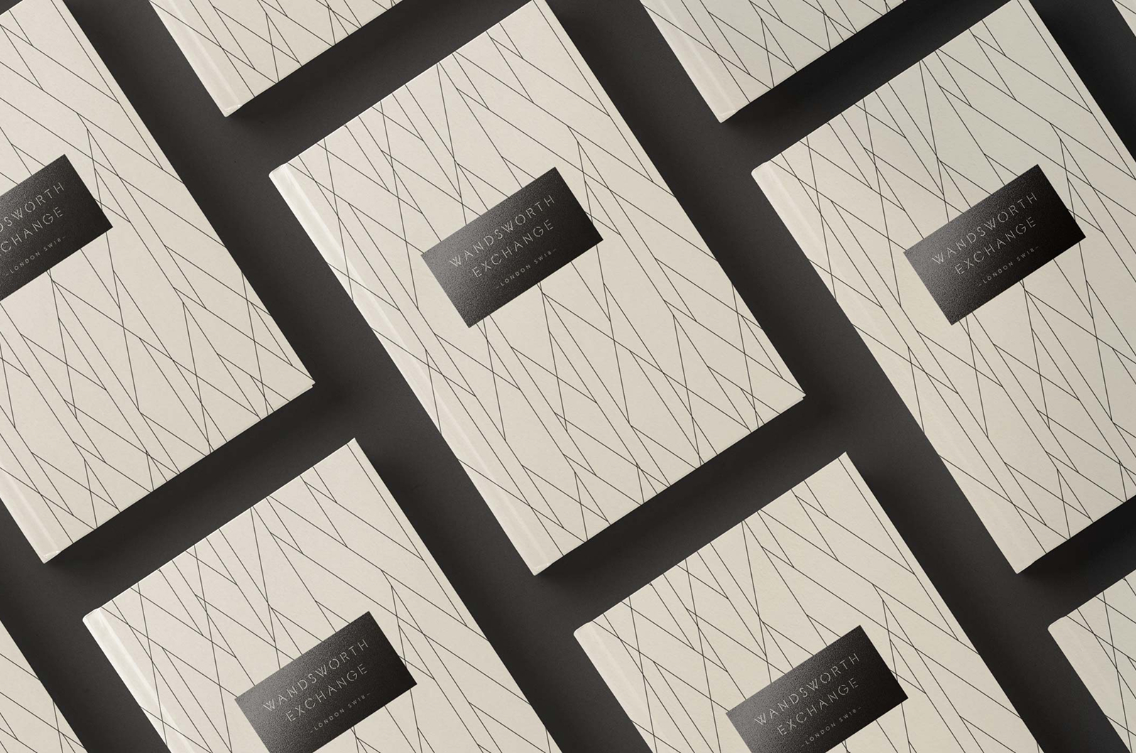 Wandsworth Exchange brochures tiled at an angle, each a fine line pattern in cream under a black band carrying the wordmark