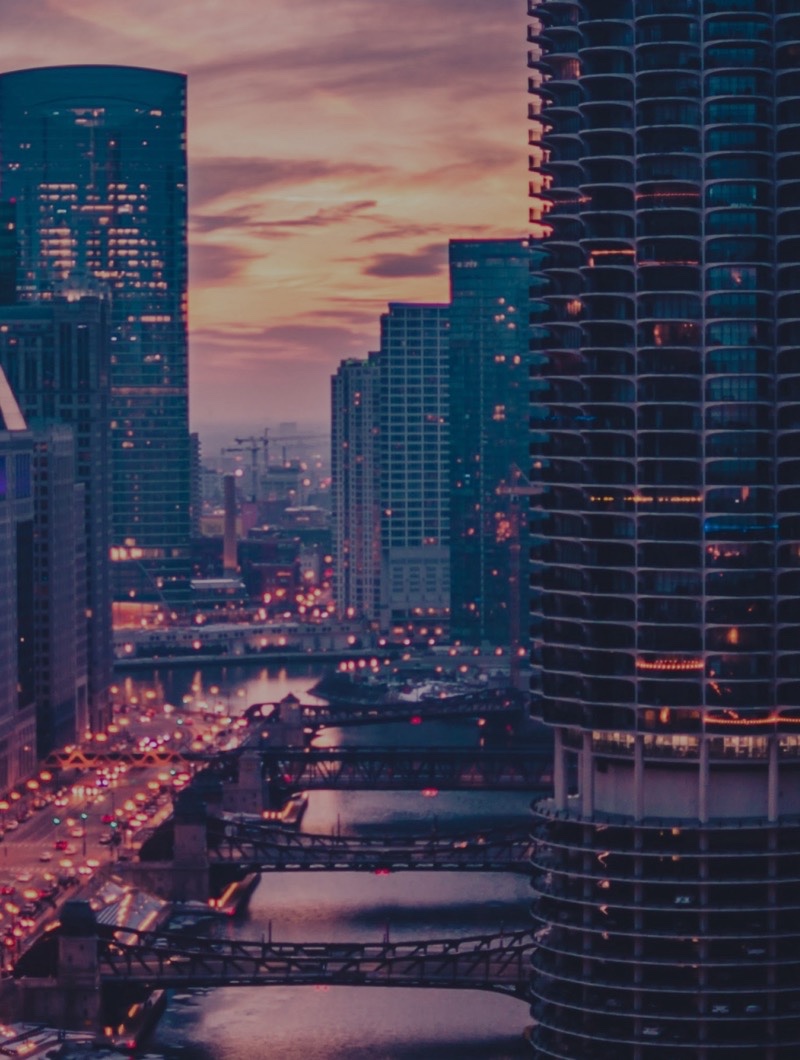 A city of high-rise towers at dusk, lit windows above a river